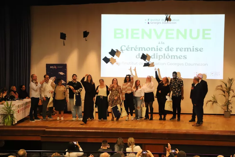 Diplômés aides-soignants sur le podium lors de la cérémonie de remise des diplômes qui jettent tous ensemble leur chapeau de diplômé en présence de formateurs et directeur